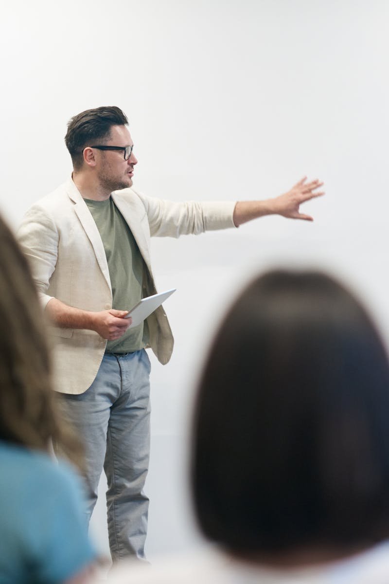 A man in a blazer gives a presentation to a captivated audience in a lecture setting.