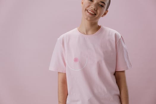 Smiling person in pink shirt symbolizing breast cancer awareness with abstract design.